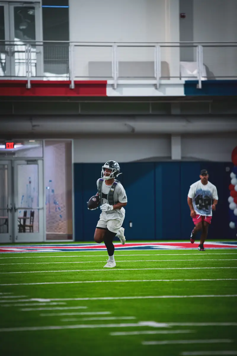 Craig LeBlanc coaching a wide receiver on an indoor football field, DFW athlete training