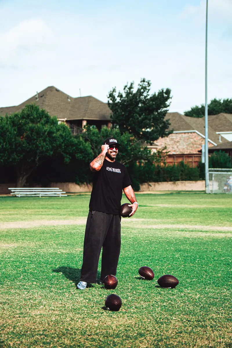Craig LeBlanc smiling on a football field with footballs, DFW athlete development and NIL mentor