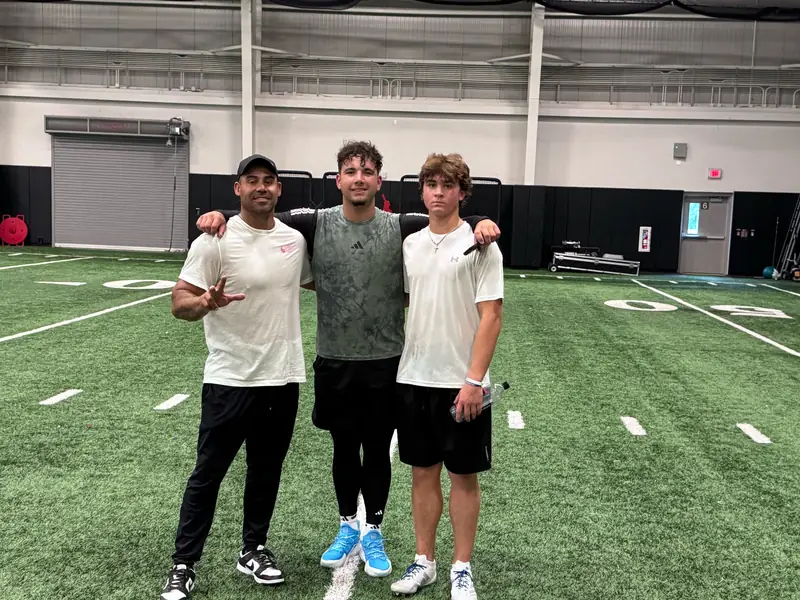 Craig LeBlanc with two athletes at an indoor football training facility